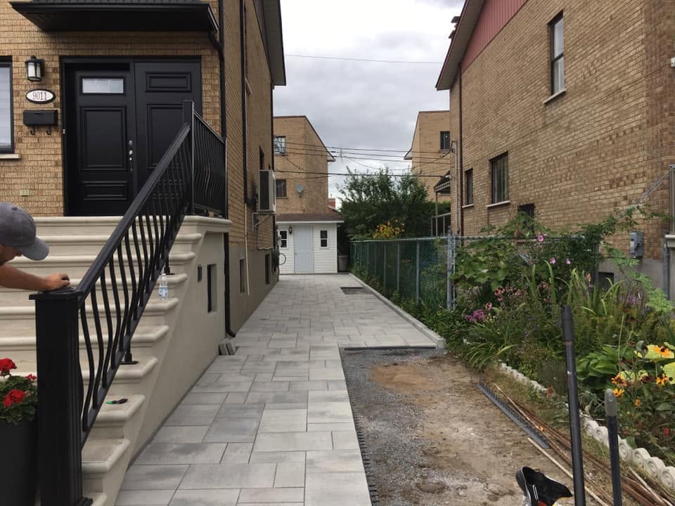 Allée latérale piétonne en pavé uni entre deux résidences